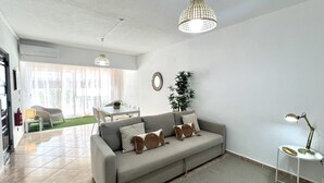 Een moderne woonkamer met een grijze bank, een eettafel en twee hanglampen.