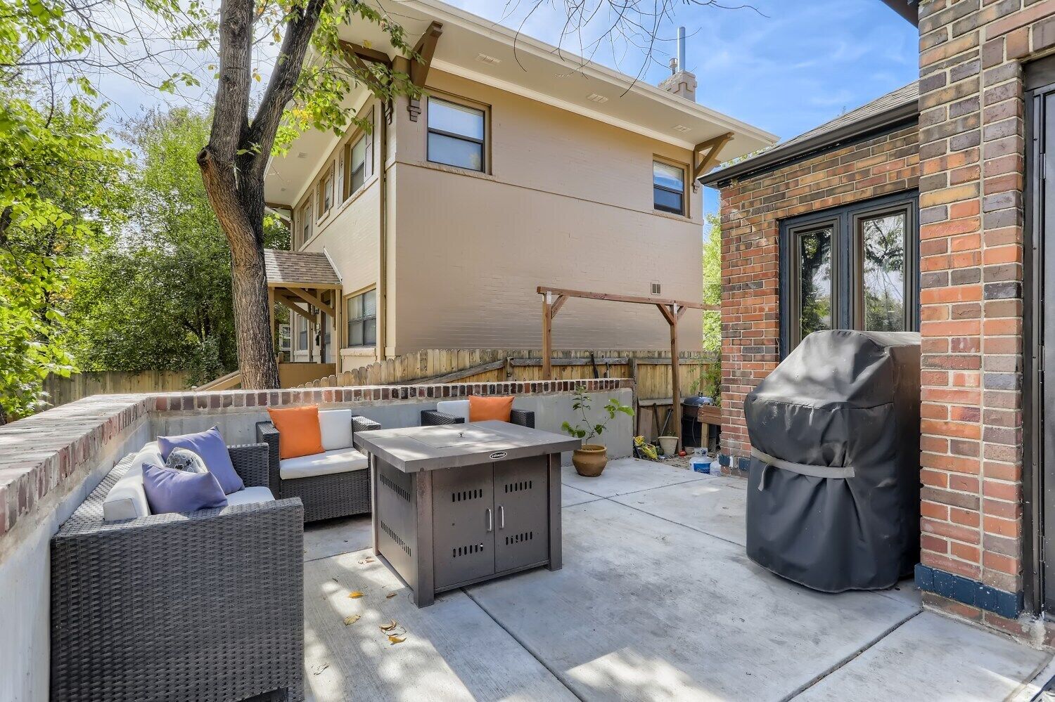 Un patio con mobiliario exterior, una parrilla y una pérgola.