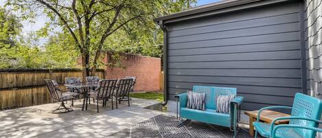 A patio with a table and chairs, a blue sofa, and a patterned rug.