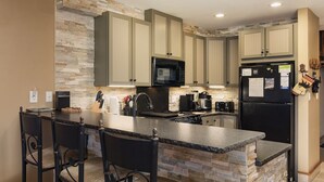 A kitchen with a central island, stone backsplash, and modern appliances. - Summit Style | AC, Pool, Hot Tub, Golf & Ski (Durango)