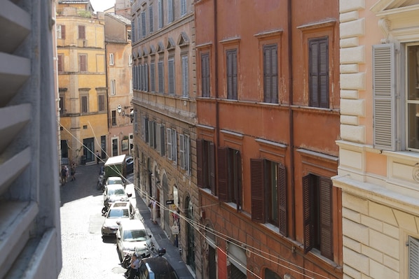 A narrow street lined with multi-story buildings, parked cars, and visible street signs. - Artsy and Elegant Apartment near Pantheon (Roma)