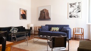 A living room with a sofa, a coffee table, a chair, and artwork on the walls. - Artsy and Elegant Apartment near Pantheon (Roma)