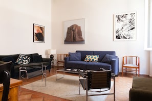 A living room with a sofa, a coffee table, a chair, and artwork on the walls.
