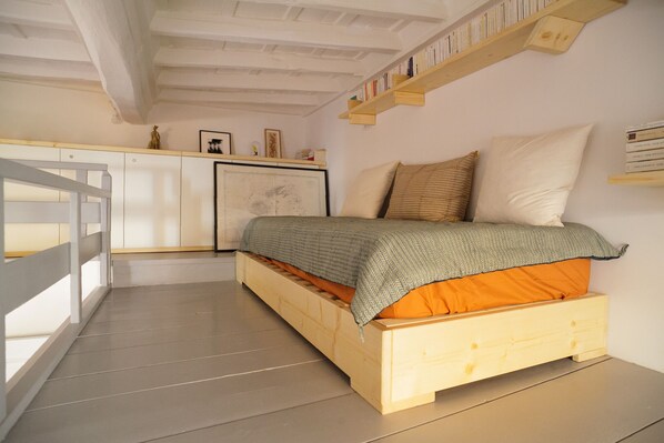 A bedroom with a bed, a desk, and a bookshelf.