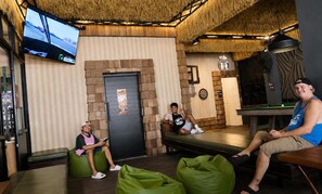 A room with a billiards table, a television mounted on the wall, and a door with a poster. - KOKO Hostel- Adults Only  (Krabi)