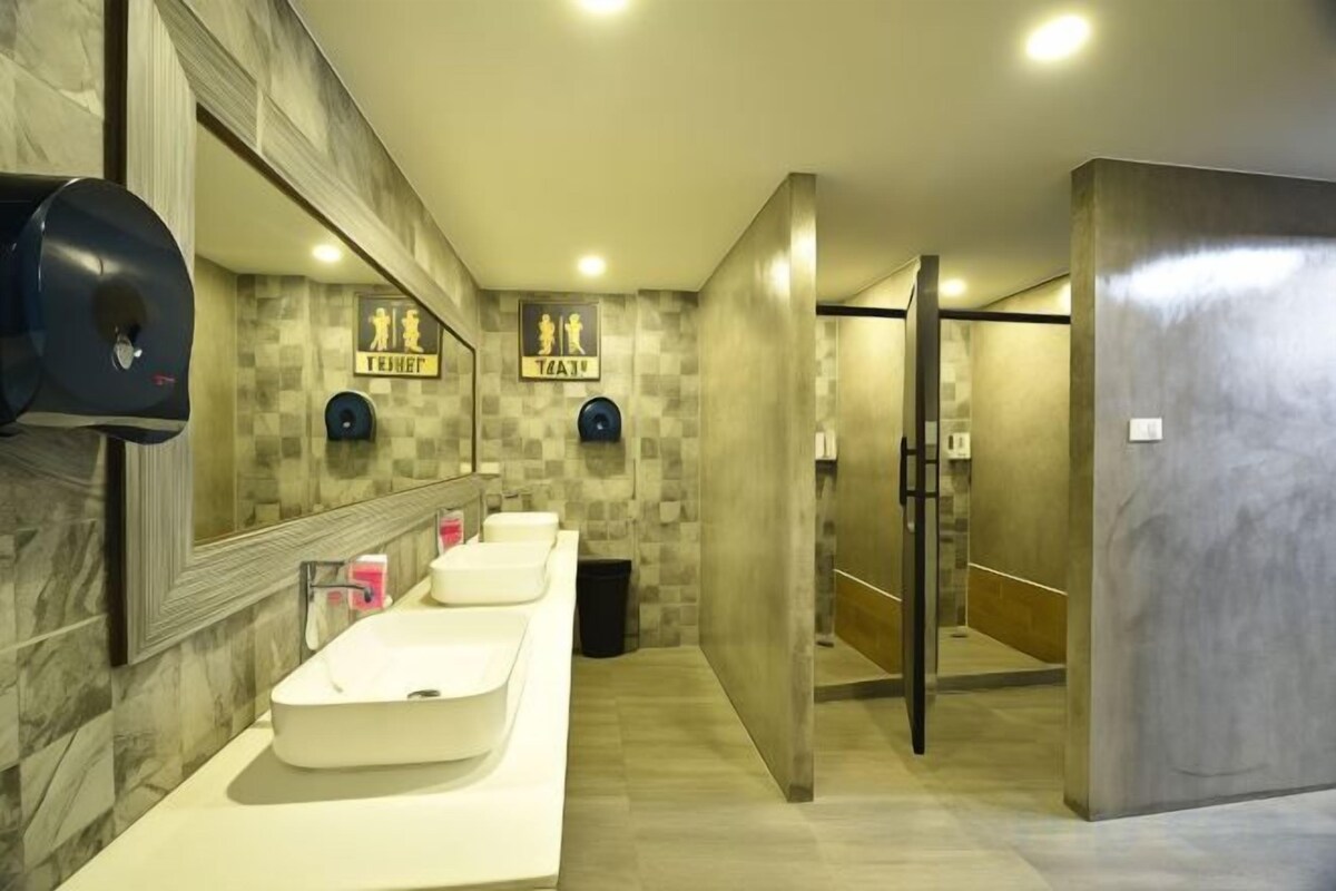 A modern bathroom with three sinks, a hand dryer, and a mirror.