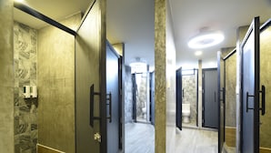 A modern bathroom with marble walls, a wooden floor, and a glass shower enclosure. - KOKO Hostel- Adults Only  (Krabi)