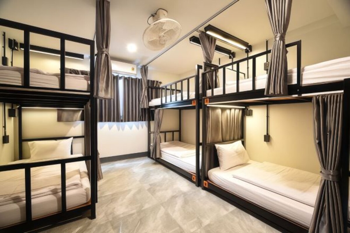 A bunk room with multiple beds, curtains, and a ceiling fan.