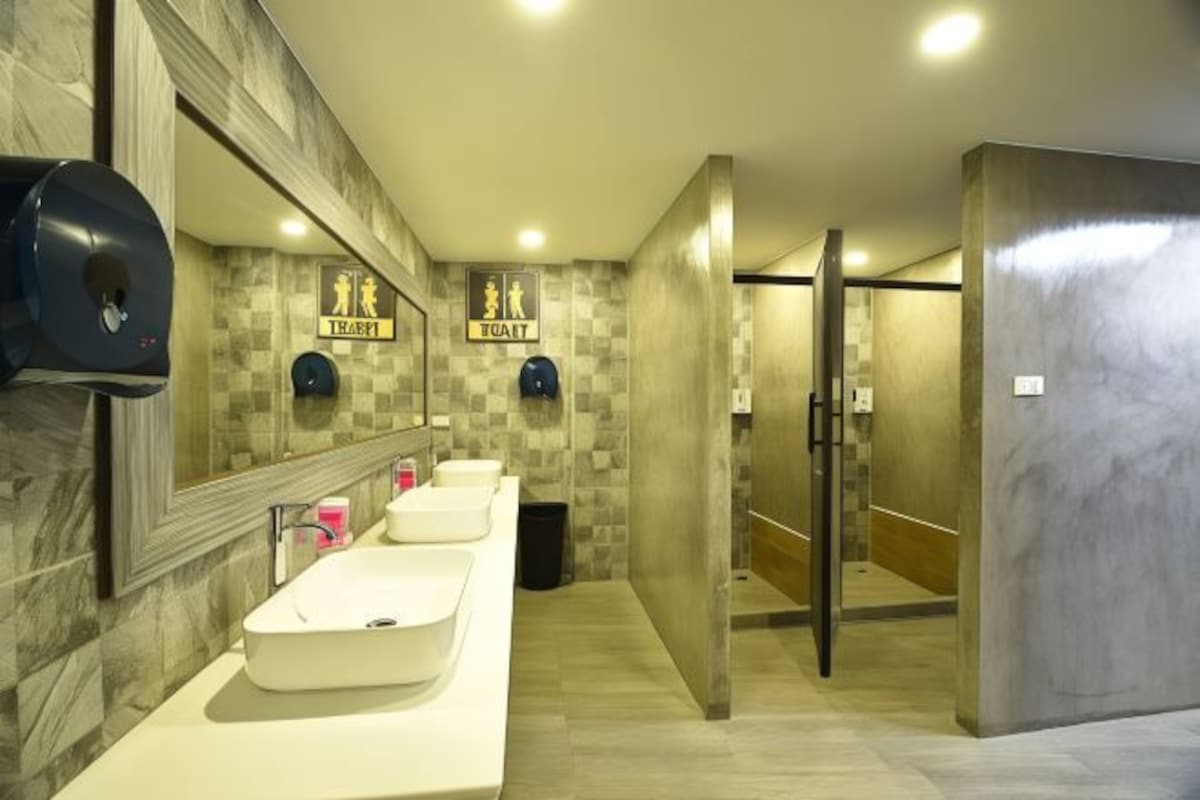 A modern bathroom with a long counter, two sinks, a hand dryer, and a mirror.