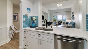Una cocina moderna con armarios blancos, lavavajillas de acero inoxidable y un salpicadero de azulejos azules.