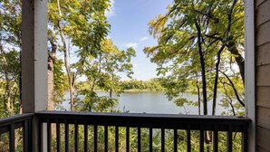 A view from a porch overlooking a lake surrounded by trees.