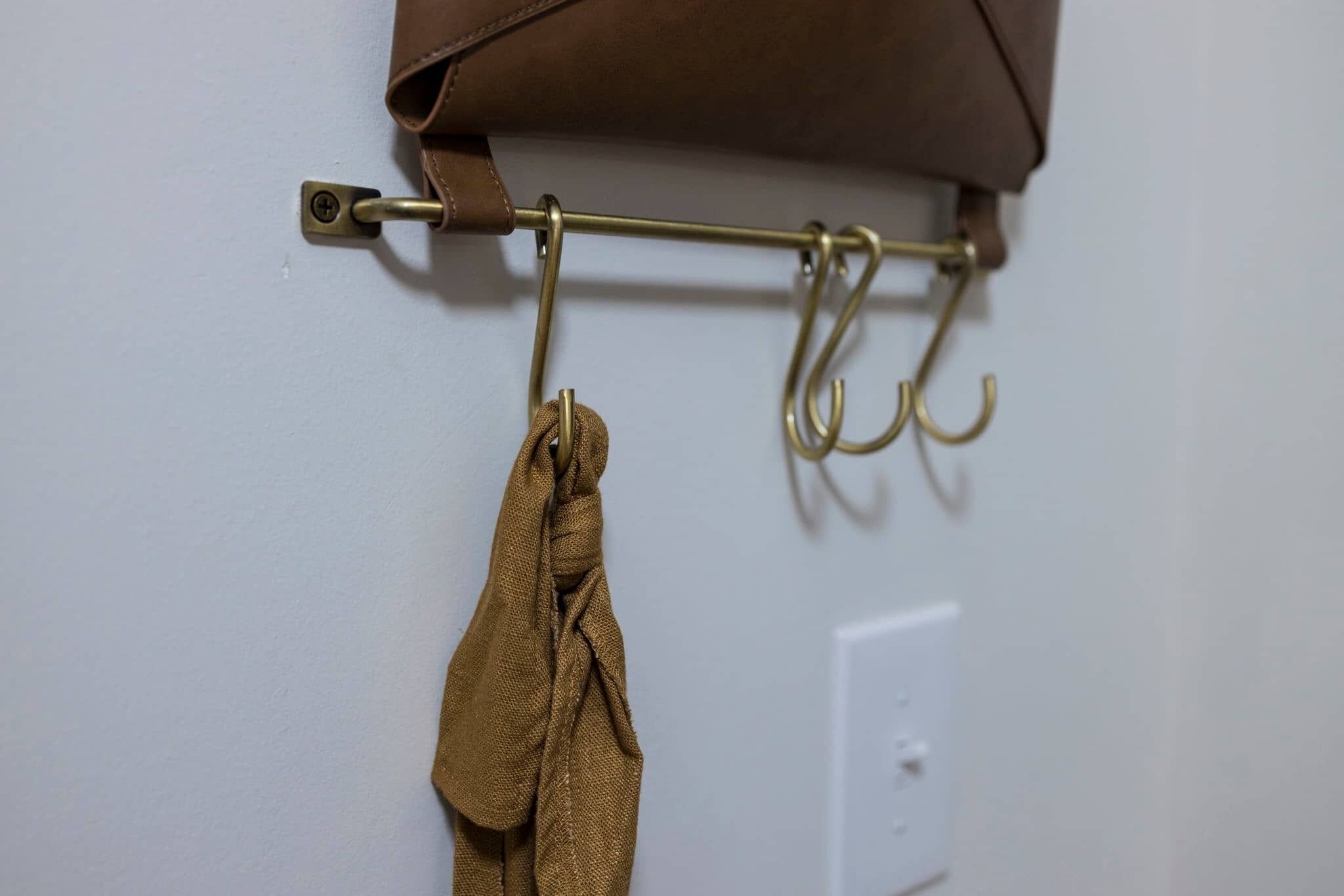 A wall-mounted towel rack with a brown towel and a hook.