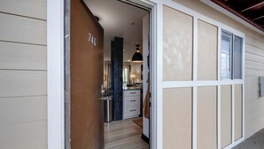 A hallway with a wooden door marked "746", leading to a kitchen area with a countertop and cabinets.