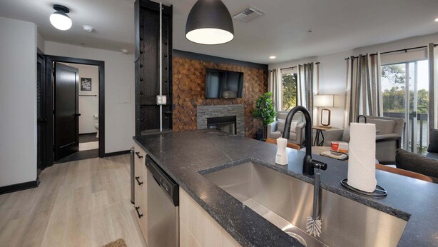 A modern kitchen with a central island, a built-in oven, and a dining area with a sofa and table.