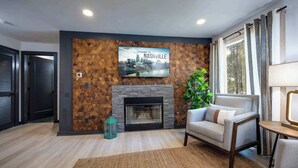 A modern living room with a fireplace, a cityscape wall art, a sofa, and a potted plant.