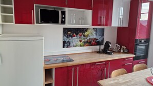 A modern kitchen with red and white cabinets, a microwave, a coffee maker, and a refrigerator. - Hipster Suites - Chez Axelle (Colmar)