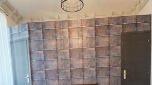 A bedroom with a bed, a wooden table, a woven rug, and a wall with a metal panel design. - Hipster Suites - Chez Axelle (Colmar)