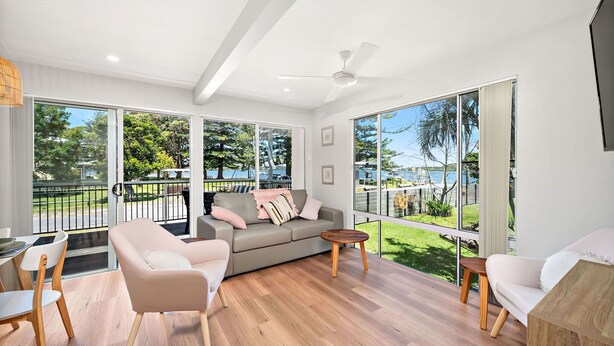 A spacious living room with a large window overlooking a balcony and a view of the sea. - Sunset Sails Taylors Beach NSW (Taylors Beach)