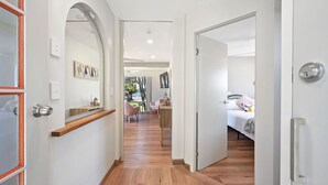 A hallway leading to a bedroom with a bed, a desk, and a chair. - Sunset Sails Taylors Beach NSW (Taylors Beach)