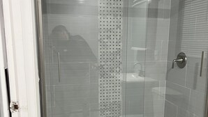 A modern shower enclosure with a glass door, a visible showerhead, and a toilet in the adjacent bathroom. - 1 bedroom 1 bath private entrance (Bay Shore)