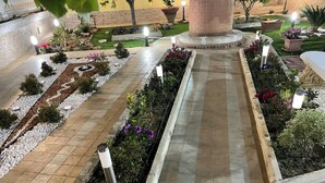 A well-maintained garden area with tiled pathways, flower beds, and decorative lighting. - Nicole House (Reggio Calabria)