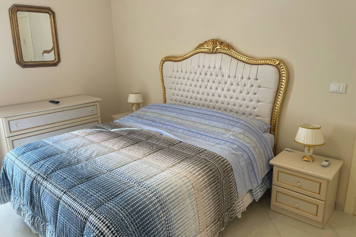 A bedroom with a bed, nightstands, a dresser, a mirror, and a lamp.