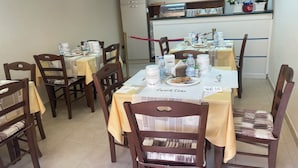 A dining area with tables set for a meal, chairs, a buffet station, and a television on the wall. - Nicole House (Reggio Calabria)