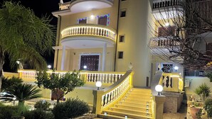 A multi-story building with a central staircase, a balcony with railings, and a well-lit entrance. - Nicole House (Reggio Calabria)