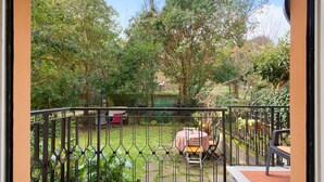 Un jardin clos avec une table et des chaises, un petit étang et diverses plantes.