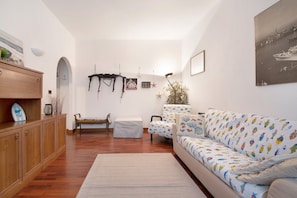 Un salón con un aparador de madera, un banco, un sof á estampado con un motivo de peces y un cuadro en la pared.