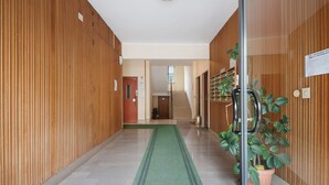 Un couloir aux murs lambrissés, recouvert d’une moquette verte et agrémenté d’une plante en pot.