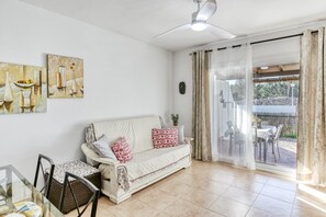Een woonkamer met een bank, stoelen, een glazen tafel en kunst aan de muur.