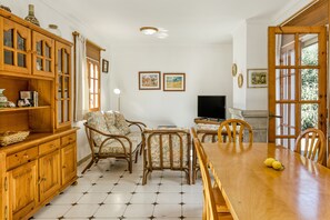 Un comedor con una mesa de madera, sillas y un televisor.