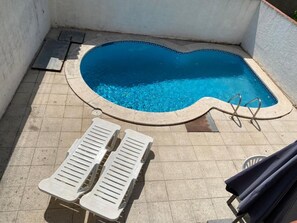 A swimming pool with a tiled deck, two lounge chairs, and a pool ladder. - Holiday Home "Casa Saguer" with Terrace, Garden & Pool (L'Escala)