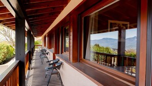 Un espace extérieur aménagé, abrité et doté de tables et de chaises, de grandes fenêtres offrant une vue sur les montagnes et d’une terrasse en bois.