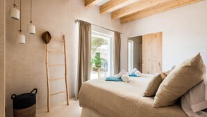 Une chambre à coucher avec un lit, des poutres en bois, une échelle, une fenêtre et un panier en osier.