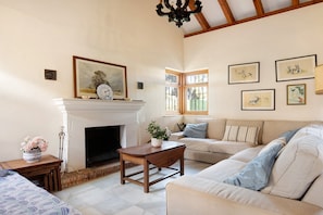 A living room with a fireplace, a sofa, a coffee table, and framed artwork on the walls.