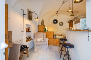 A cozy room with a cushioned chair, a wooden cabinet, and a bar stool.