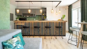 Una cocina moderna con una isla central, luces colgantes y taburetes de bar.