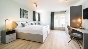 Un dormitorio moderno con cama, mesitas de noche, un escritorio y una silla.