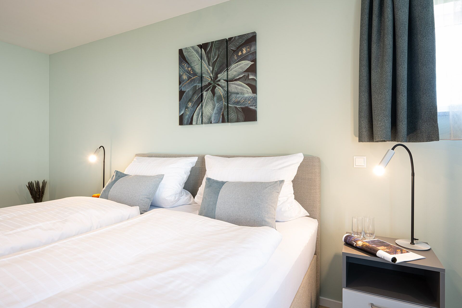 Una habitación de hotel con una cama, dos mesitas de noche y una obra de arte colgada en la pared.