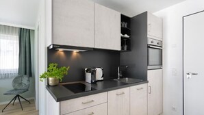 Una cocina moderna con armarios de madera clara, encimera negra y electrodomésticos de acero inoxidable.