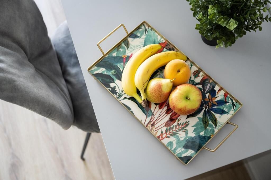A tray with bananas, pears, and an apple on a table.