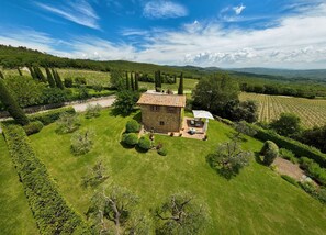 A stone house with a tiled roof surrounded by well-maintained gardens and vineyards. - San Donato Retreat by Arceno Rentals Club - Concierge, Pool, Wifi (San Gusmè - Castelnuovo Berardenga)