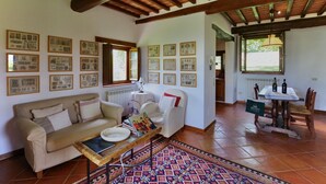 Un saló acollidor amb un sofà, una taula de centre i una catifa estampada. Hi ha quadres a les parets i una finestra amb vista a l'exterior.