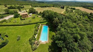 Vista aèria d'una propietat amb piscina, gespes verdes exuberants i vinyes al fons.