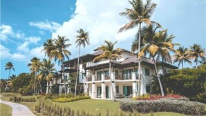 A multi-story house with a well-maintained lawn and palm trees.