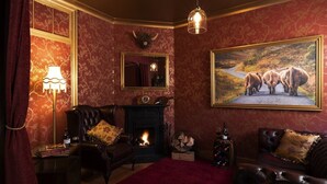 A room with a fireplace, a large painting of bison, a mirror, and a chandelier. - Stay at-FL (Crawley)
