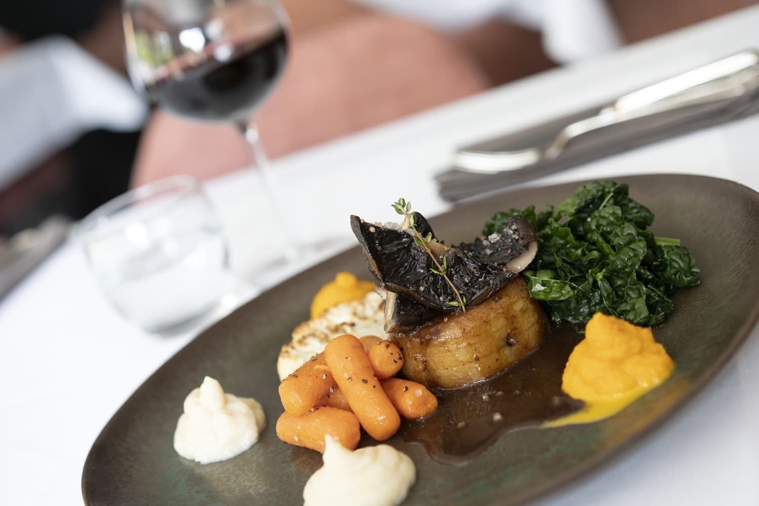 A plate of food with a variety of vegetables and a glass of red wine.