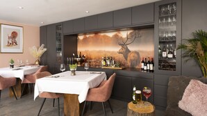 A modern bar area with a large mural of a deer, wine bottles, and glasses on shelves. - Stay at-FL (Crawley)